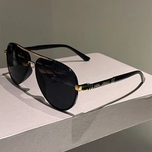 Detail of pilot sunglasses showing black frame with gold metal hinges and side engraving