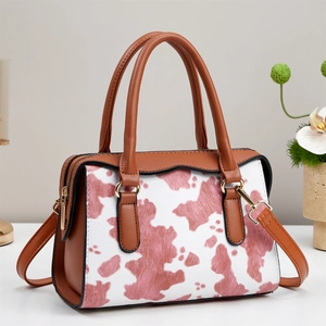 Detail of pink cow print tote bag with brown leather handles and gold-tone metal hardware