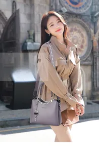 Detail of lavender pebble leather handbag featuring metal chain and embroidered wide strap