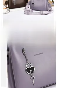 Detail of fashion tote bag with heart charm and wide patterned shoulder strap