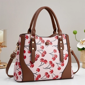 Chic pink crossbody bag with red cherry print and dark brown leather straps