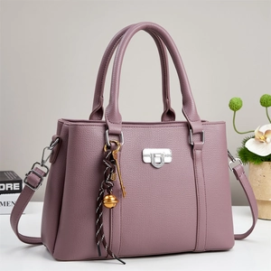 Close-up of mauve lychee grain faux leather bag featuring silver hardware and tassel charm