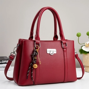 Detail of burgundy lychee grain leather bag with silver lock and decorative pendant