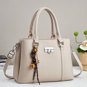 Close-up of beige lychee grain leather handbag with silver twist lock and decorative charms