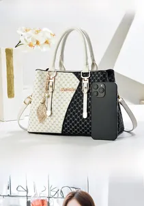 Detail of a geometric tote bag featuring DH monogram pattern and gold metal leaf charm