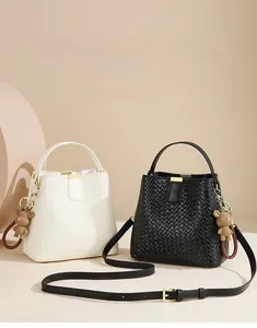 Detail of woven bucket bags in black and white with gold clasp and plush bear charm