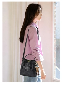Close-up of black woven bucket bag with elegant leather texture and cute bear charm