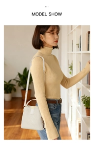 Detailed shot of white textured bucket bag with fluffy charm and thin shoulder strap