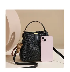 Size comparison of black woven bucket bag with smartphone and teddy bear charm