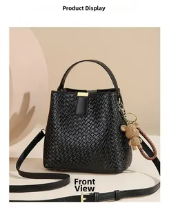 Detailed front view of a black woven bucket bag with leather handles and gold hardware