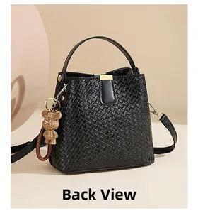 Detailed back view of black woven leather bucket bag with wide strap and bear charm