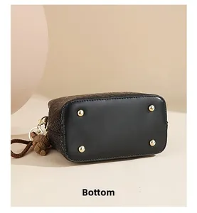 Detailed bottom view of black woven bucket bag featuring four protective gold metal studs