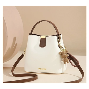 Detail of woven bucket bag featuring gold FASHION logo and cute bear keychain accessory