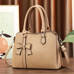Detail of light brown lychee textured tote bag with bow accent and golden studs decoration