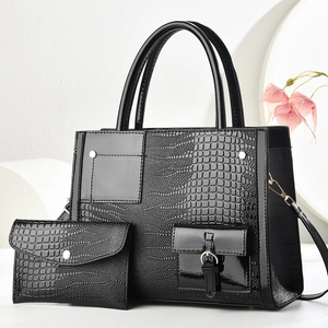 Detail of black crocodile embossed tote bag and matching wallet with glossy patent finish