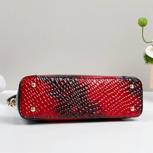 Detail view of red snake pattern handbag bottom with protective gold studs and glossy finish
