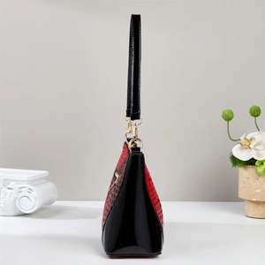Detail of red crocodile texture and black patent leather on luxury Boston handbag