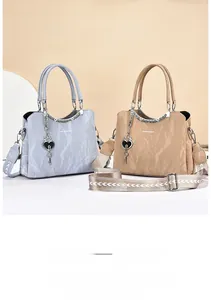 Detail of elegant pleated PU handbags with wide jacquard straps and heart charms