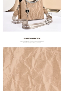 Detail of beige wrinkled texture handbag with black heart key charm and woven strap