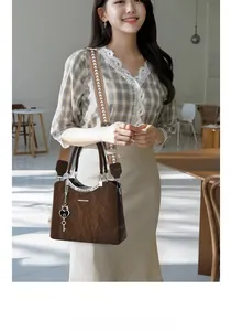Close-up of brown textured leather handbag with woven strap and fashion pendant