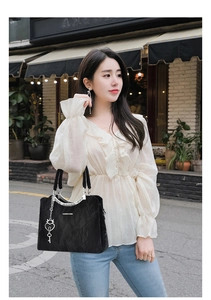 Detail of black marble textured tote with heart charm and silver hardware on street