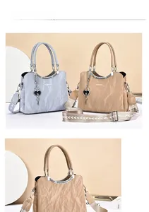 Detail of elegant handbag with pleated texture, heart pendant, and wide wavy strap