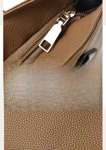 Detail of high-quality brown PU leather texture and gold-tone metal zipper on tote bag