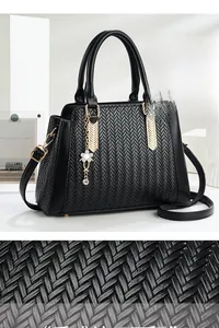 Detail of woven black leather texture with gold V-metal and white flower charm on handbag
