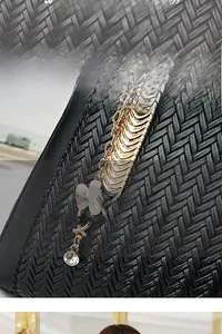 Detail of black woven texture and gold leaf pendant with crystals on luxury handbag