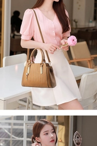 Detail of camel herringbone handbag featuring gold floral charm and adjustable strap