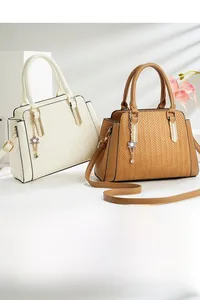 Close-up of herringbone texture on faux leather handbags with gold rings and flower charms