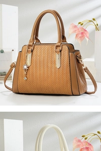 Detailed macro view of brown herringbone woven bag with golden hardware and floral charm