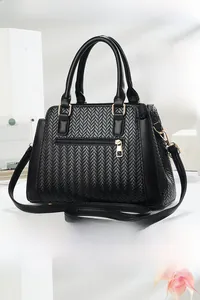 Detail view of the black woven texture handbag featuring gold hardware and a back zipper