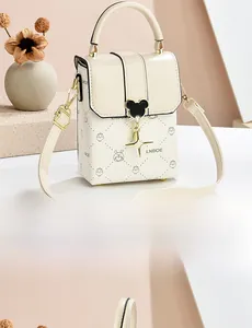 Side view of cream leather crossbody bag with cartoon print and star charm pendant