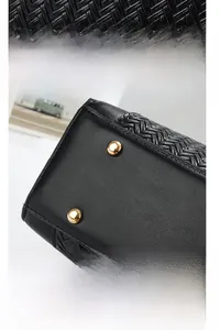 Detail of woven leather texture and protective gold metal studs on black handbag base
