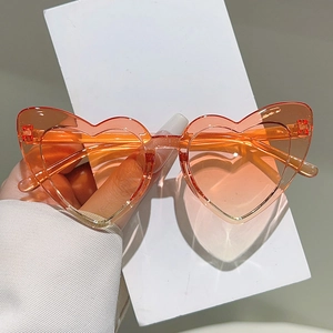 Detail of heart-shaped orange transparent sunglasses for kids, party style close-up