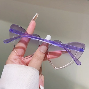 Detail of heart-shaped kids sunglasses with purple gradient lenses and clear frames