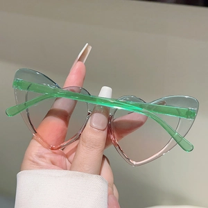 Close-up of heart-shaped sunglasses with green to pink gradient lenses and clear green frames
