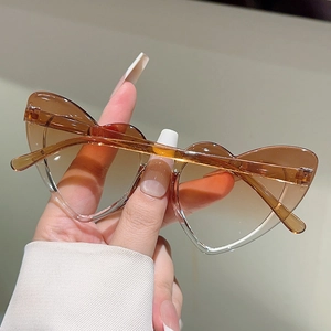 Detail of heart-shaped kids sunglasses with brown gradient lenses and transparent frame