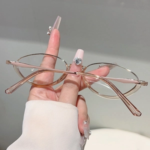 Close-up of rose gold oval metal frame glasses held by hand featuring pink temple tips