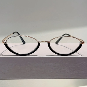 Detailed view of semi-rimless oval glasses with gold metal frames and black lower accents