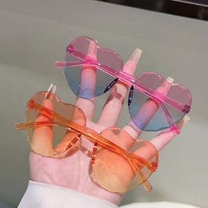 Détail de lunettes de soleil sans monture en cœur avec verres dégradés rose et orange