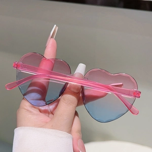 Détail des verres dégradés rose-bleu sur lunettes de soleil cœur sans monture enfant
