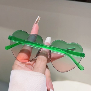 Gros plan de lunettes de soleil en forme de cœur avec verres dégradés vert-rose et monture