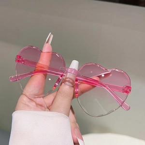 Détail de lunettes de soleil cœur sans monture avec verres roses dégradés et biseautés