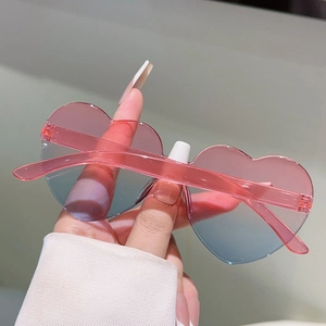 Detail of heart-shaped rimless sunglasses with pink-blue gradient lenses and pink temples
