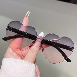 Detail of heart-shaped rimless sunglasses with purple to pink gradient lenses and black temples