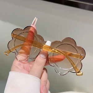 Détail des lunettes de soleil fleurs ambrées translucides pour enfants à la main