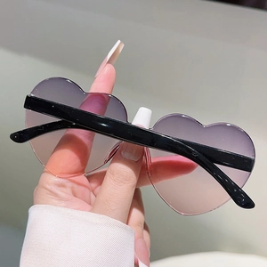 Detailed shot of heart-shaped sunglasses featuring purple gradient lenses and black frames