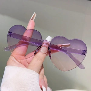 Close-up of heart-shaped rimless sunglasses with purple to champagne gradient lenses